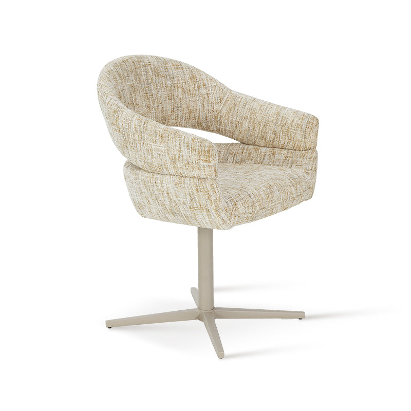 A beige and yellow linen fabric swivel dining chair with a hollow backrest and light-colored metal legs, positioned next to a round wooden table on a rug.