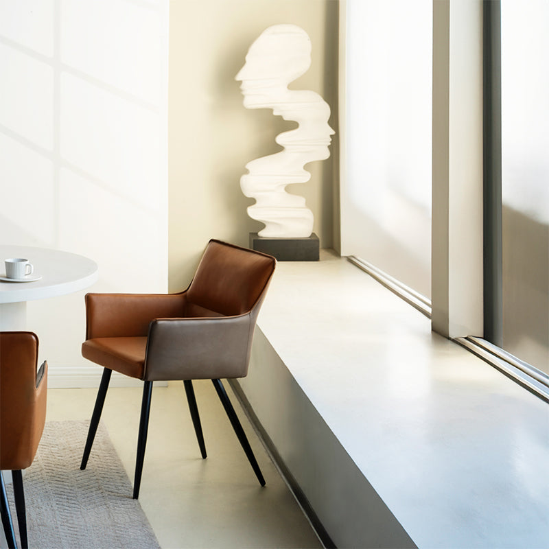 Elevate dining with Kaya’s PU leather armchairs featuring two tone patchwork upholstery, foam padded seat, and black steel legs for a modern, durable finish.